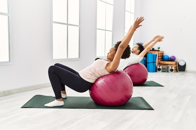 Jovem afro-americana e hispânico exercitando na sala de pilates, alongando o corpo e fazendo pose de ioga, treinando força e equilíbrio