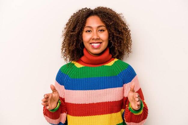 Jovem afro-americana isolada em fundo branco segurando algo com ambas as mãos apresentação do produto