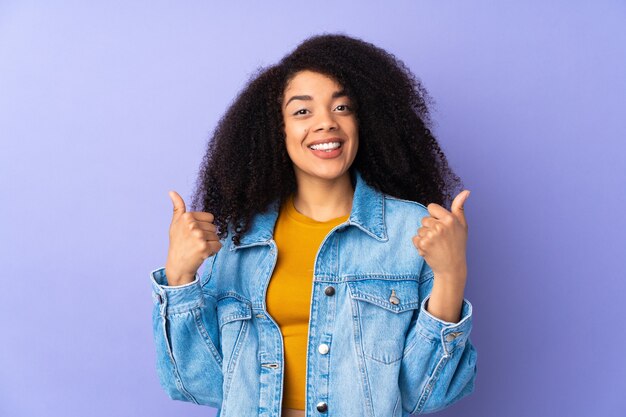 Jovem afro-americana isolada em roxo fazendo um gesto de polegar para cima