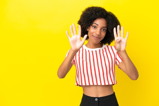 Jovem afro-americana isolada em um fundo amarelo contando nove com os dedos