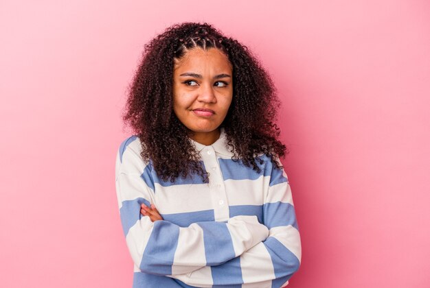 Jovem afro-americana isolada em um fundo rosa sonhando em alcançar objetivos e propósitos.