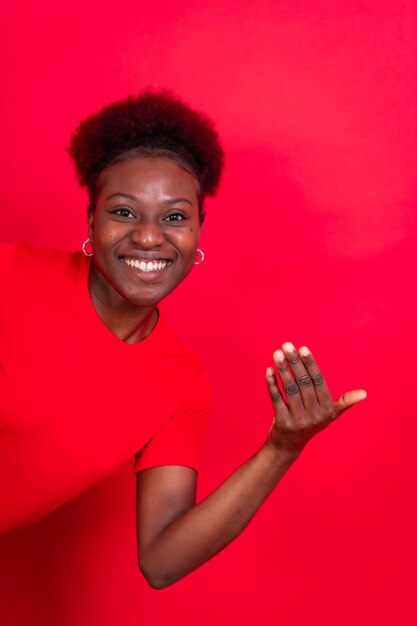 Jovem afro-americana isolada em um fundo vermelho convidando para vir com a mão