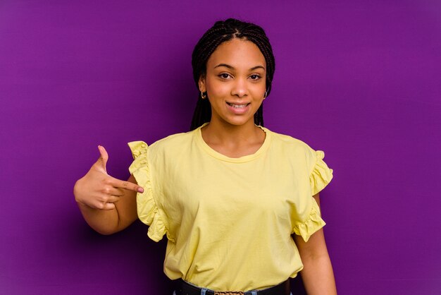 Jovem afro-americana isolada em uma pessoa amarela apontando com a mão para um espaço de cópia de camisa, orgulhosa e confiante