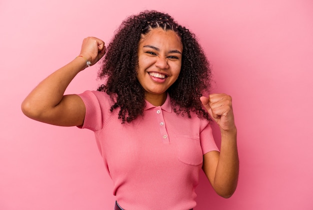 Jovem afro-americana isolada na parede rosa dançando e se divertindo