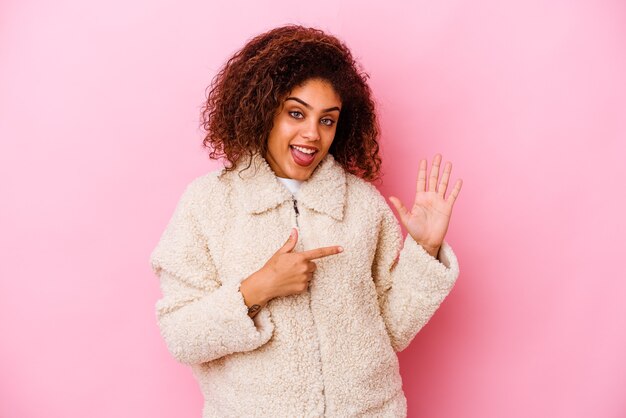 Foto jovem afro-americana isolada na parede rosa sorrindo alegre mostrando o número cinco com os dedos