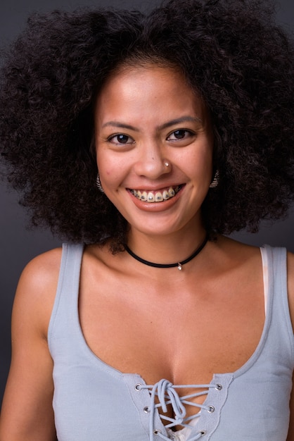 Foto jovem afro-americana multiétnica com cabelo afro contra uma parede cinza
