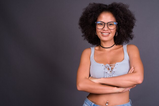 jovem afro-americana multiétnica com cabelo afro contra uma parede cinza