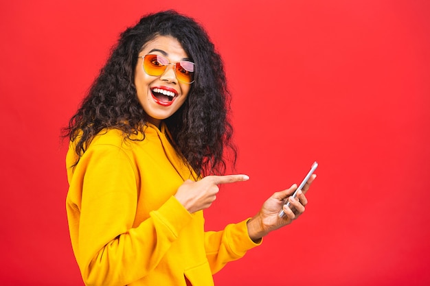 jovem afro-americana negra com um telefone celular isolado sobre fundo vermelho