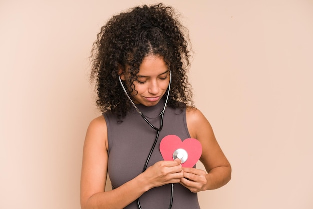 Jovem afro-americana ouvindo um coração com um estetoscópio, conceito de amor