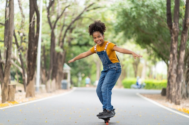 Foto jovem afro-americana se divertindo andando de skate no verão ao ar livre.