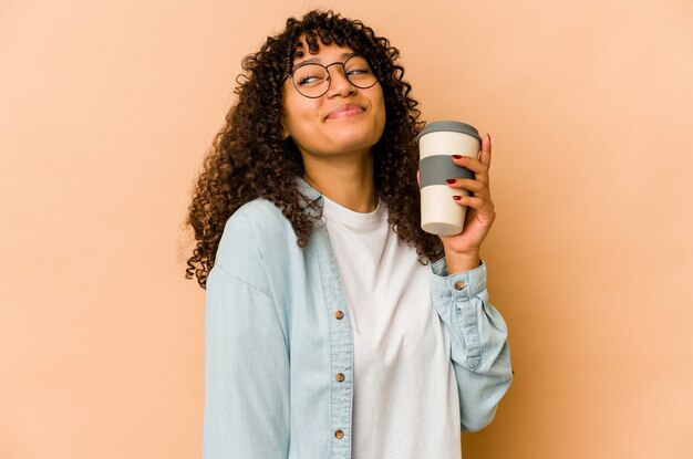 Jovem afro-americana segurando um café para viagem, sonhando em alcançar objetivos e propósitos