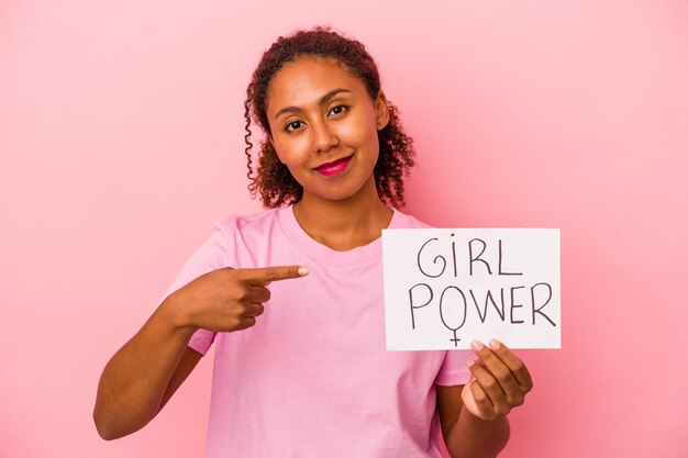 Jovem afro-americana segurando um cartaz do poder feminino isolado em um fundo rosa