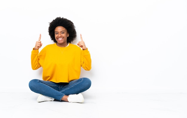 Jovem afro-americana sentada no chão apontando para uma ótima ideia