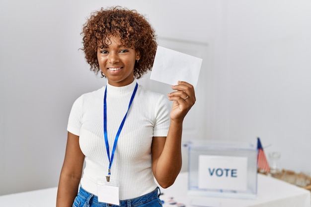 Foto jovem afro-americana sorrindo confiante segurando voto no colégio eleitoral