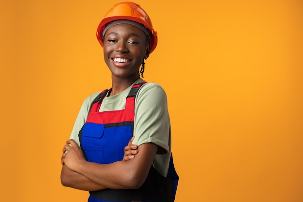 Jovem afro-americana usando capacete de arquiteto contra fundo amarelo