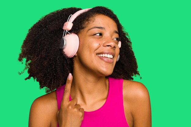 Jovem afro-americana usando fones de ouvido e dançando isolada