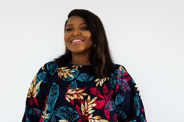 Jovem afro-americana usando vestido posando sobre parede branca em casa inclusão e diversidade co