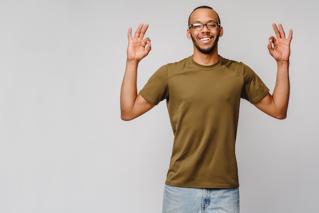 Jovem afro-americano alegre e amigável com camiseta verde mostrando sinal de OK