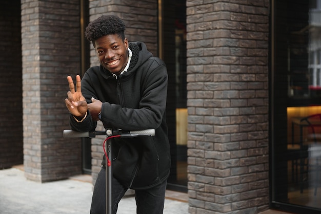 Jovem afro-americano com scooter elétrico na cidade