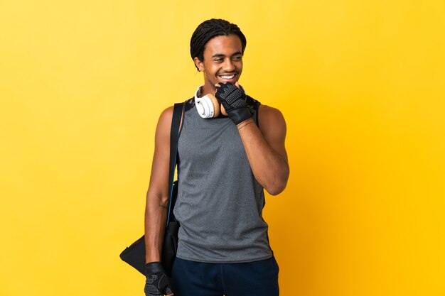 Jovem afro-americano com tranças e bolsa amarela olhando para o lado e sorrindo