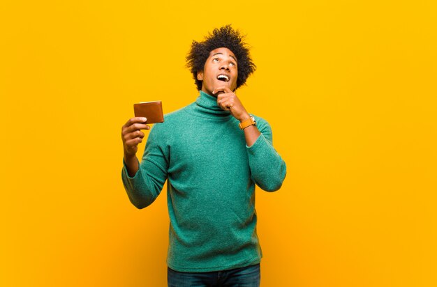 Jovem afro-americano com uma carteira contra backgrou laranja