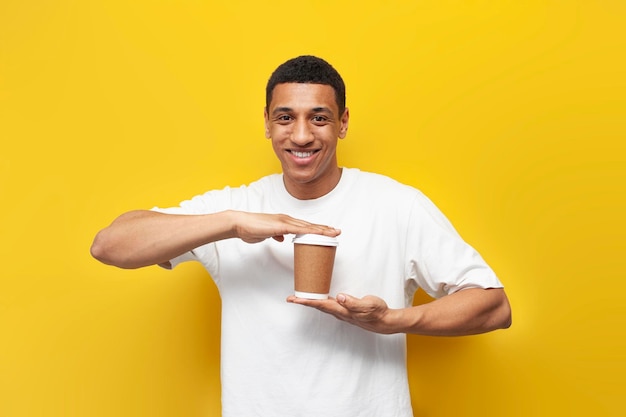 Jovem afro-americano em camiseta branca segura e recomenda café em copo de papel