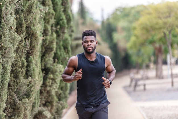 Jovem afro-americano em roupas esportivas correndo no parque