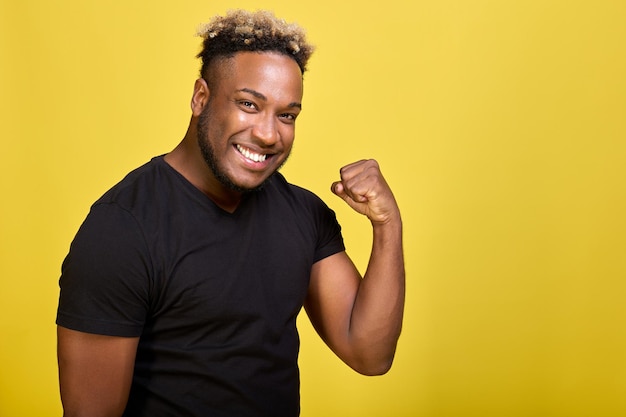 Jovem afro-americano em uma camiseta elegante está muito feliz e satisfeito