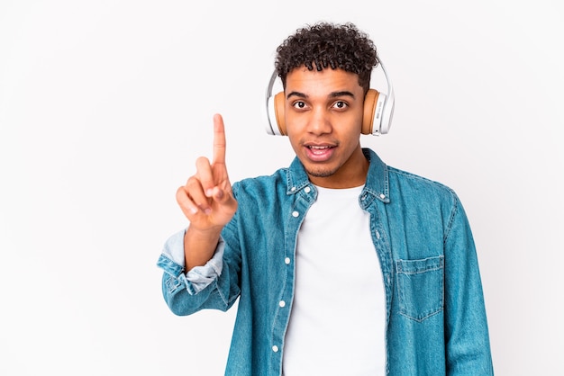 Jovem afro-americano encaracolado ouvindo música com fones de ouvido, mostrando o número um com o dedo.