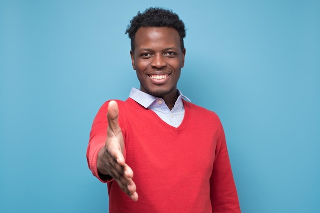 Jovem afro-americano estendendo a mão em direção à câmera para apertar as mãos