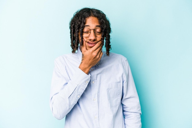 Jovem afro-americano isolado em fundo azul com uma forte dor molar de dor de dentes