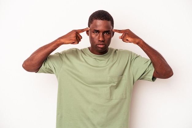 Jovem afro-americano isolado em fundo branco focado em uma tarefa mantendo os dedos apontando a cabeça