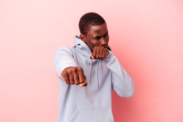 Jovem afro-americano isolado em fundo rosa jogando um soco de raiva lutando devido a um argumento de boxe