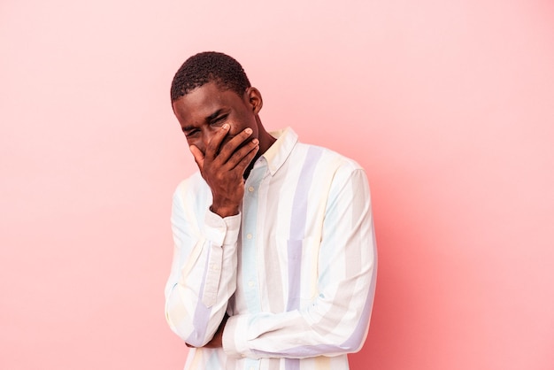 Jovem afro-americano isolado em fundo rosa rindo feliz emoção natural despreocupada