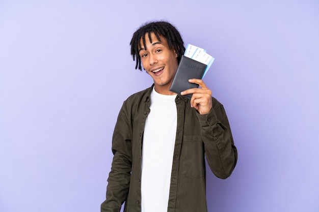 Jovem afro-americano isolado em roxo feliz em férias com bilhetes de avião e passaporte