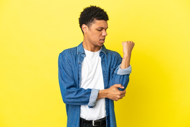 Foto jovem afro-americano isolado em um fundo amarelo com dor no cotovelo