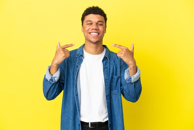 Jovem afro-americano isolado em um fundo amarelo fazendo um gesto de polegar para cima