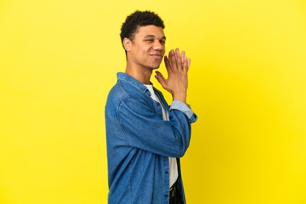 Foto jovem afro-americano isolado em um fundo amarelo tramando algo