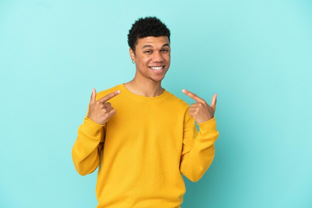 Jovem afro-americano isolado em um fundo azul fazendo um gesto de polegar para cima