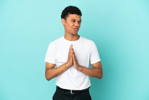 Jovem afro-americano isolado em um fundo azul tramando algo