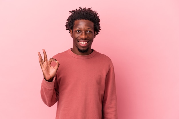 Jovem afro-americano isolado em um fundo rosa alegre e confiante, mostrando um gesto de ok.