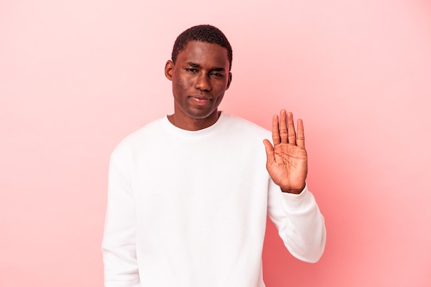 Jovem afro-americano isolado em um fundo rosa, sorrindo alegre mostrando o número cinco com os dedos.