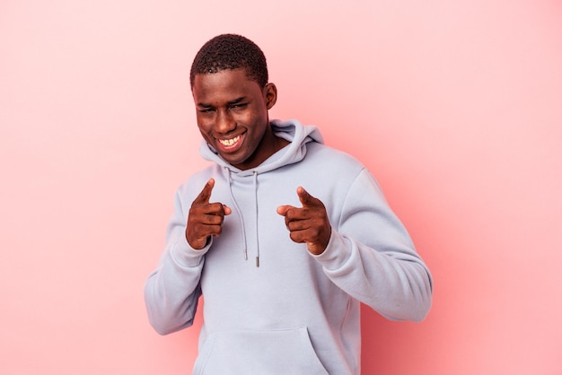 Jovem afro-americano isolado no fundo rosa, apontando para a frente com os dedos.