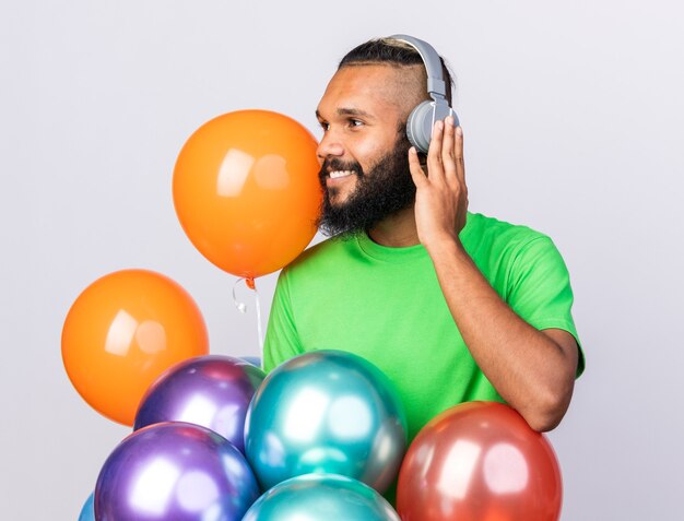 Jovem afro-americano satisfeito com fones de ouvido isolados na parede branca