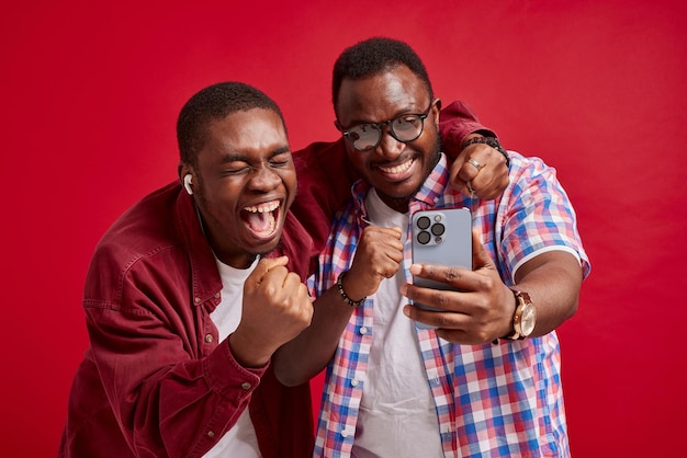 Jovem afro-americano se alegra com as mãos para a câmera isolada no retrato de estúdio de fundo vermelho