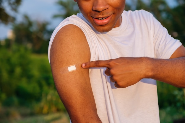 Jovem afro-americano sorridente mostrando a mão com esparadrapo