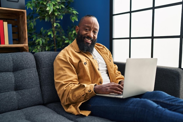 Jovem afro-americano usando smartphone sentado no sofá em casa