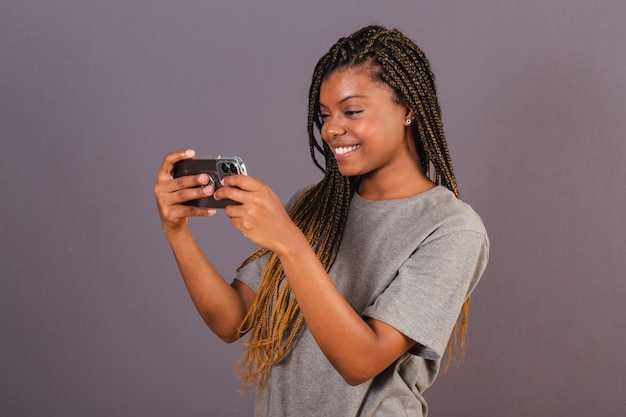 Jovem afro brasileira assistindo algo pelo smartphone celular