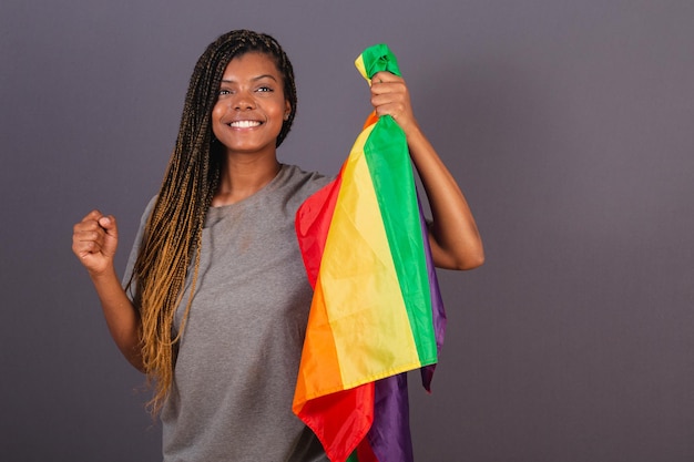 Jovem afro brasileira segurando a bandeira LGBT LGBTQ na forma de militância Empoderamento da diversidade