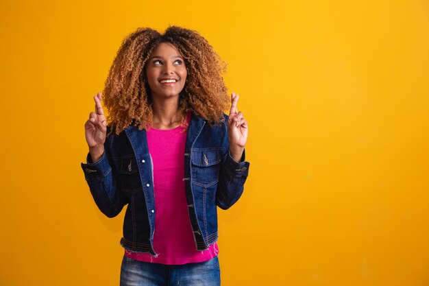 Jovem afro com dedos cruzados. Sorte